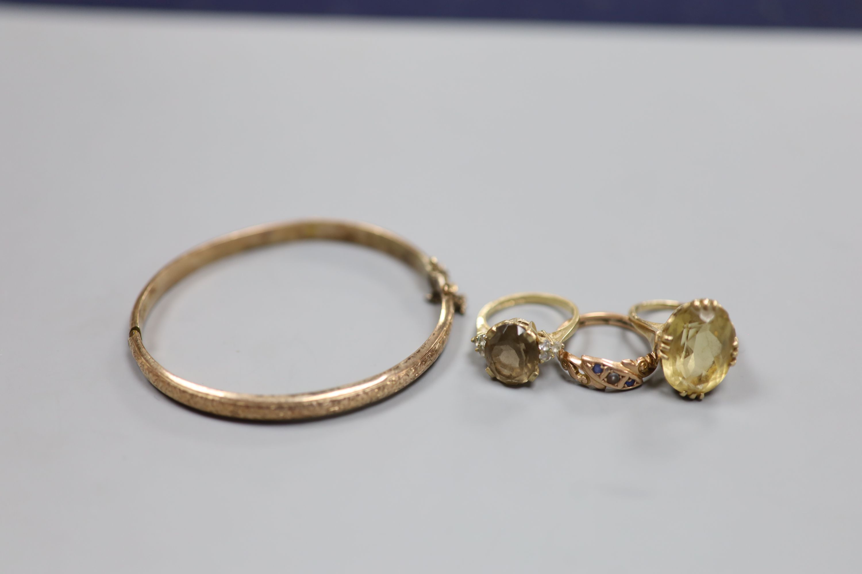 Three assorted 9ct and gem set rings and a 9ct gold hinged bangle